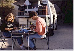 Susanne und Reto sitzen am Campingtisch, dahinter steht unser VW-Bus