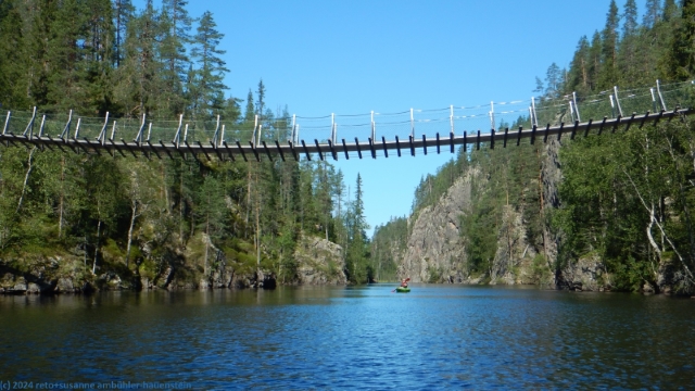 susanne im kajak unter der haengebruecke ueber den julma-oelkky im hossa nationalpark