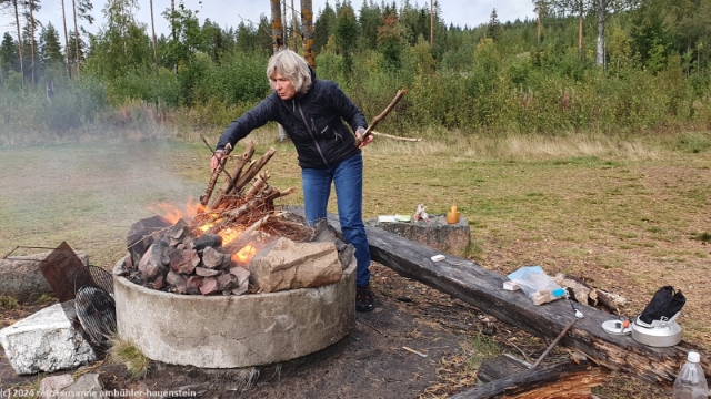 susanne entfacht ein feuer in der feuerstelle beim camp brintbodarna