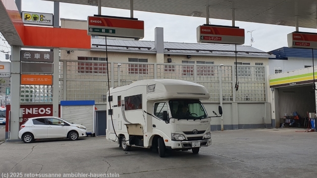 unser camper an einer tankstelle mit haengenden schlaeuchen in sapporo